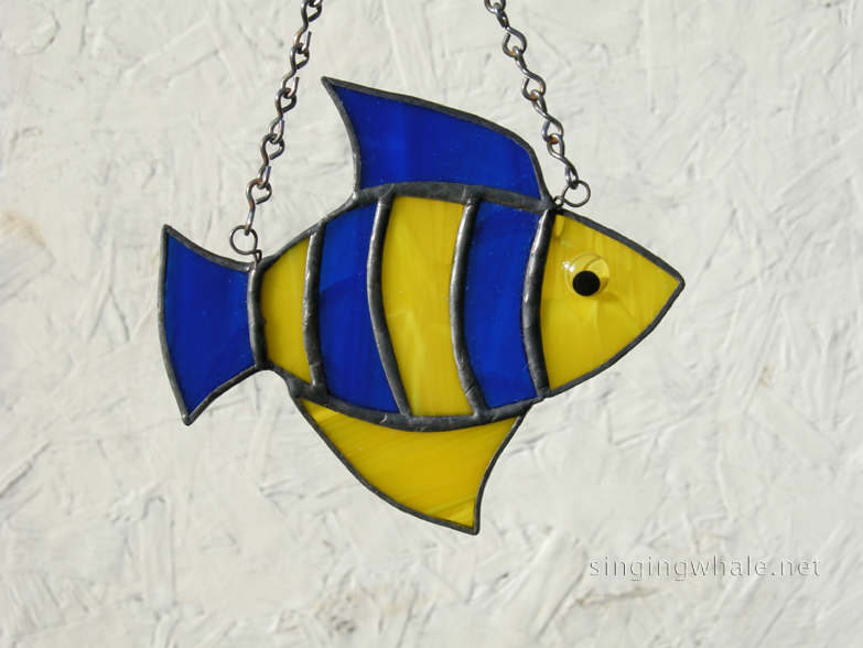 Made of dark blue wispy and yellow wispy glass. Eye is a yellow wiggle eye securely glued on. Finished in a pewter patina. Measures 4 3/4 " wide by 4" tall. Fish in this pattern are $15 each.