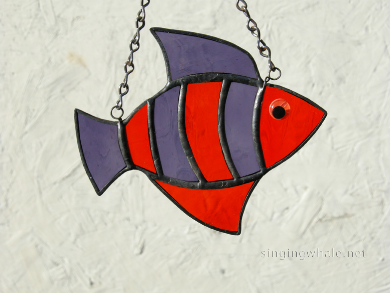 Made of orange and purple waterglass. Eye is an orange wiggle eye securely glued on. Finished in a pewter patina. Measures 4 3/4 " wide by 4" tall. Fish in this pattern are $15 each.